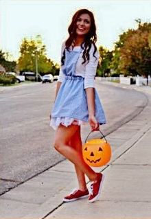 a young woman is holding a pumpkin in one hand and smiling at the camera while wearing red tennis shoes