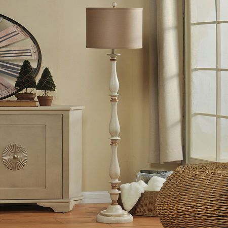 a white lamp sitting on top of a wooden floor next to a dresser and mirror