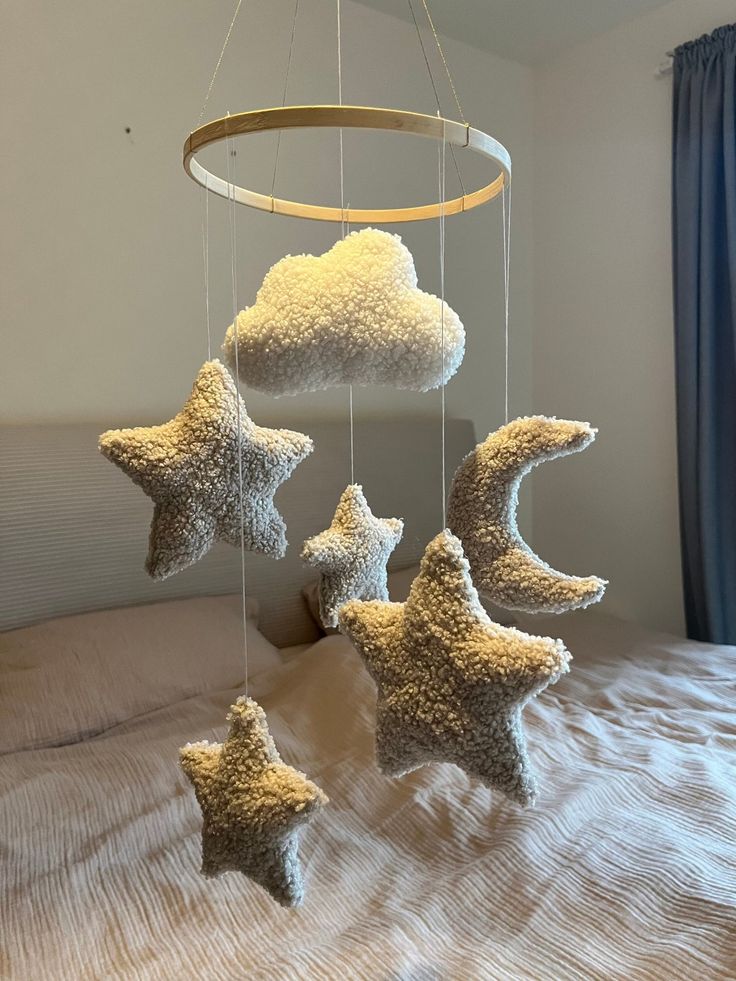 a bed with three stars hanging from it's sides and a cloud in the middle