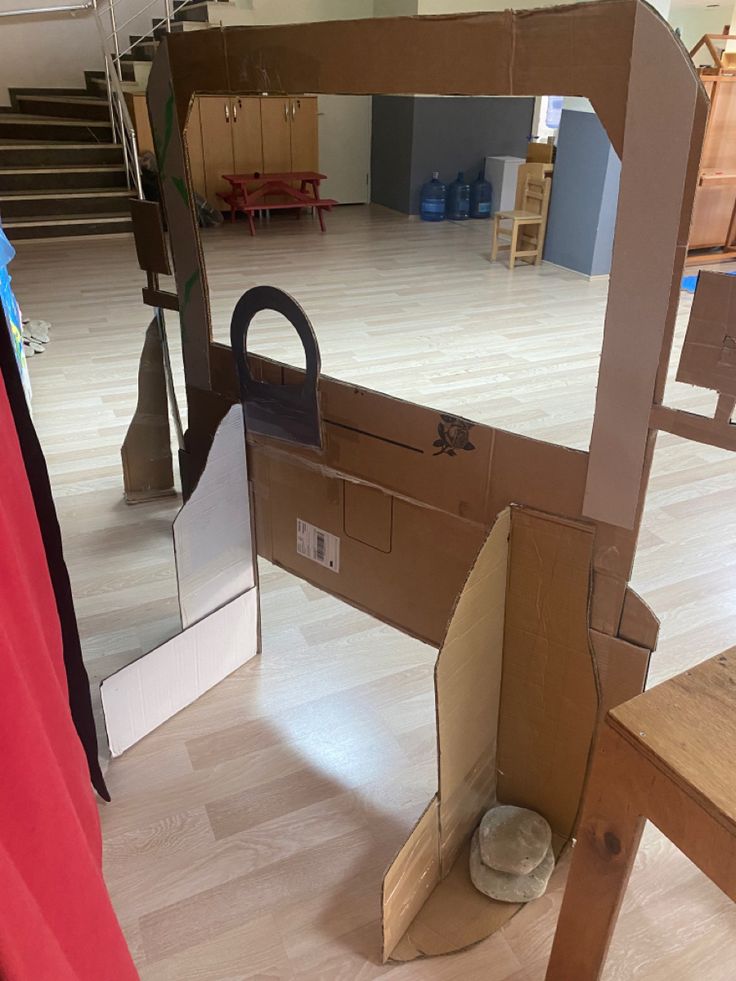 an open cardboard box sitting on top of a hard wood floor next to a chair