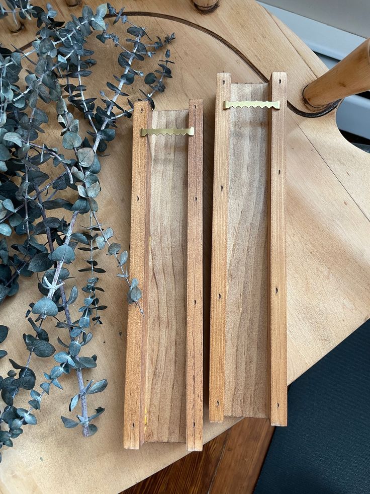 two pieces of wood sitting on top of a wooden table next to flowers and scissors