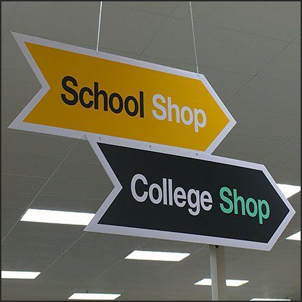 two yellow and black signs hanging from the ceiling in an office building that says school shop, college shop