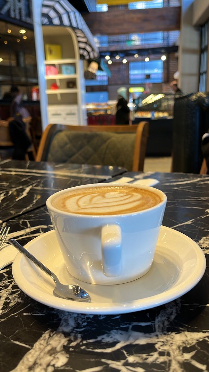 a cappuccino sits on a saucer at a table in a restaurant