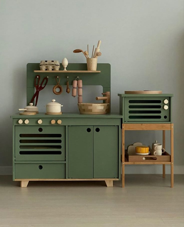 a kitchen with green cabinets and wooden utensils