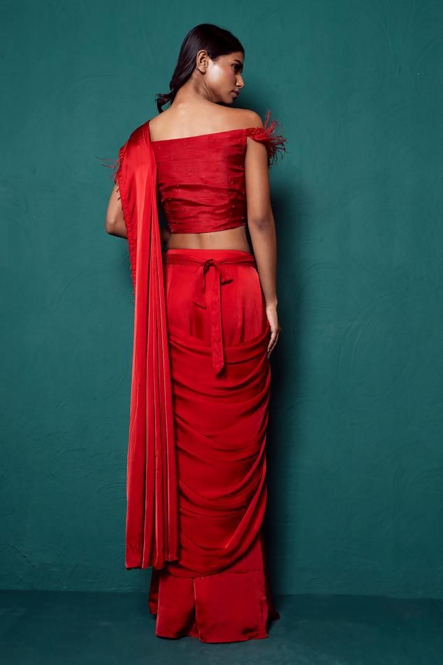 Red pre-draped plain saree in satin silk base with dangling beads on hem. Paired with off shoulder padded blouse with all over french knots bloom embroidery, feather detailing on the sleeves and embroidered belt.
Components: 3
Pattern: Embroidery
Type Of Work: French Knots
Neckline: Straight Neck
Sleeve Type: Off Shoulder
Fabric: Satin Silk
Color: Red
Other Details: 
Padded blouse
Length:
Saree: 43inches
Blouse: 15inches
Note: The gypsie tiara worn by the model is not for sale
Occasion: Sangeet, Pre-draped Silk Sets, Elegant Red Silk Pre-draped Saree, Silk Pre-draped Saree With Draped Sleeves For Party, Draped Blouse For Diwali Evening, Draped Blouse For Evening Diwali Celebrations, Draped Evening Blouse For Diwali, Draped Blouse For Evening And Diwali, Silk Draped Blouse For Diwali, Diwali Draped Silk Blouse