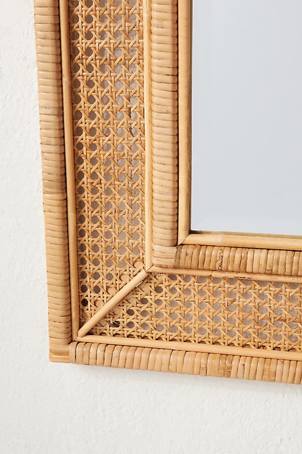 a close up of a mirror on a wall with a rattan frame and wicker pattern