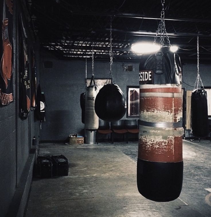 an empty gym with boxing gloves hanging from the ceiling and punching bags on the wall