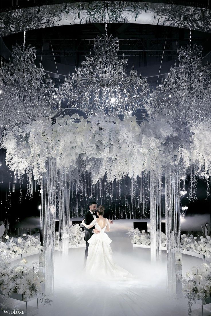 a bride and groom standing under a chandelier