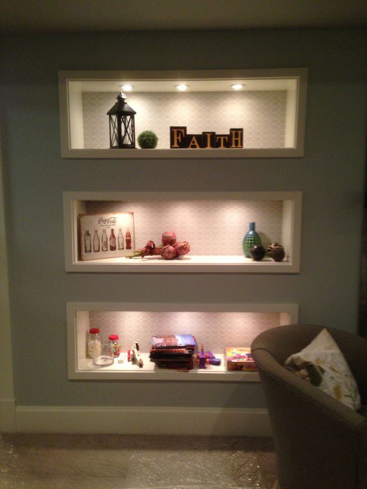 three shelves with various items on them in the corner of a room, one is lit up and the other is empty