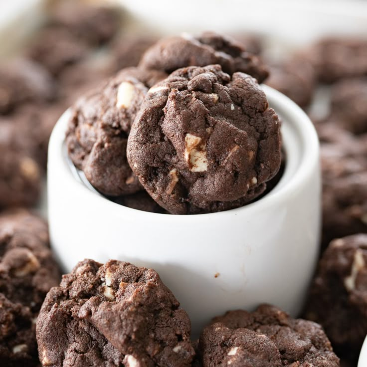 a white bowl filled with chocolate cookies on top of a table