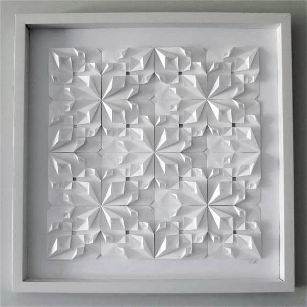 a white paper sculpture in a frame on the wall with an abstract pattern made out of folded origami pieces