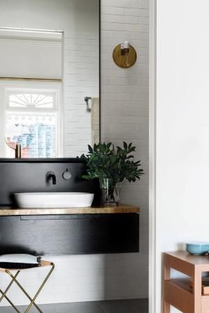 a black and white bathroom with a mirror, sink and stool in front of it