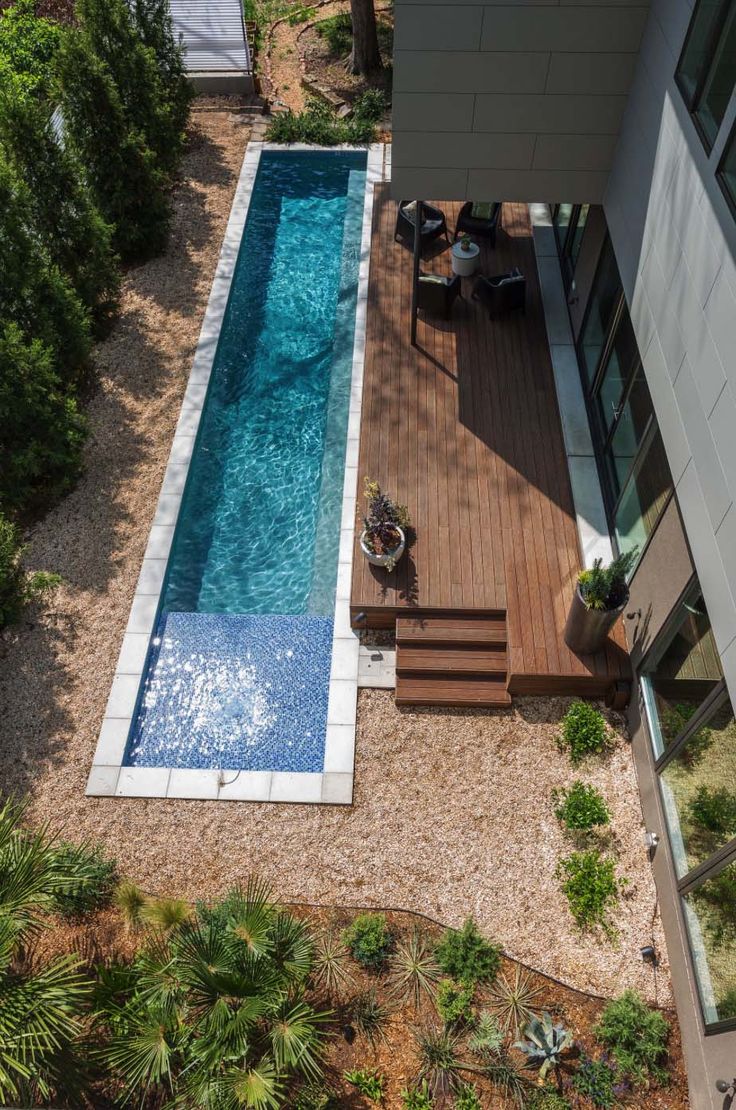 an aerial view of a swimming pool surrounded by trees and shrubs, with stairs leading up to it