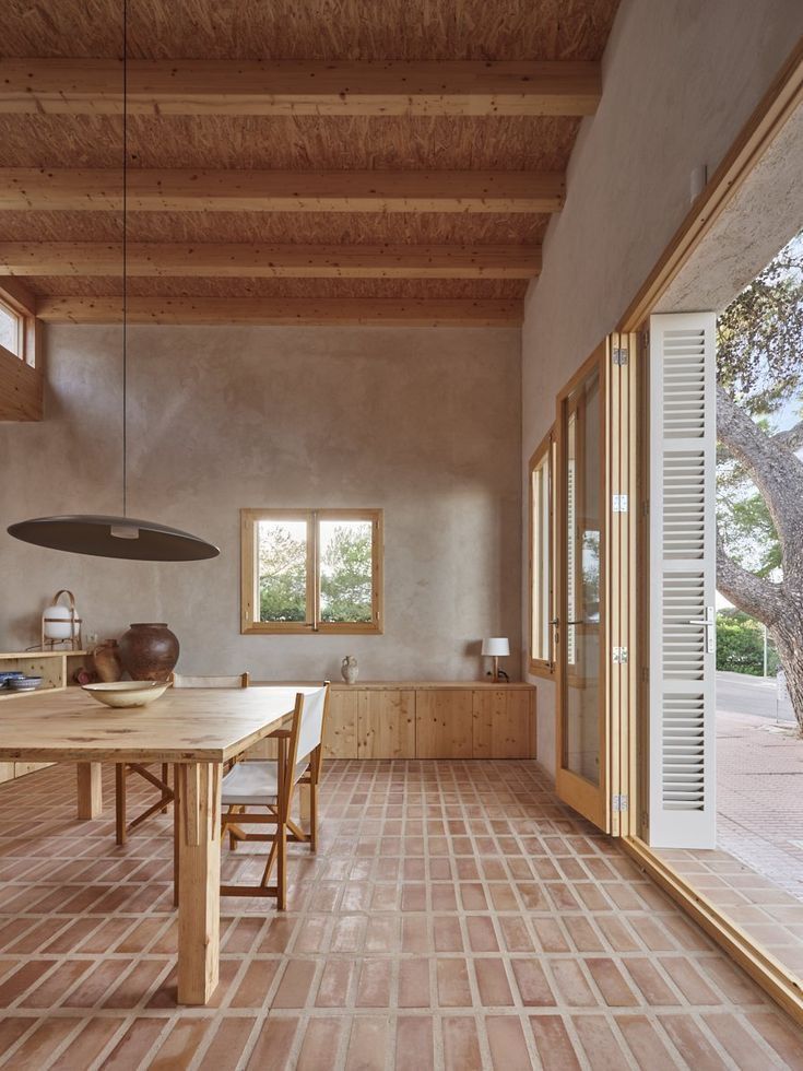 a large wooden table sitting in the middle of a room with windows on both sides