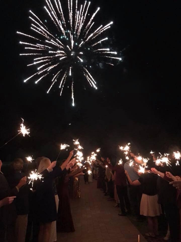 people are holding sparklers in their hands as fireworks go off