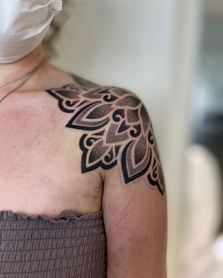 a woman with a tattoo on her shoulder wearing a surgical mask and holding a stethoscope