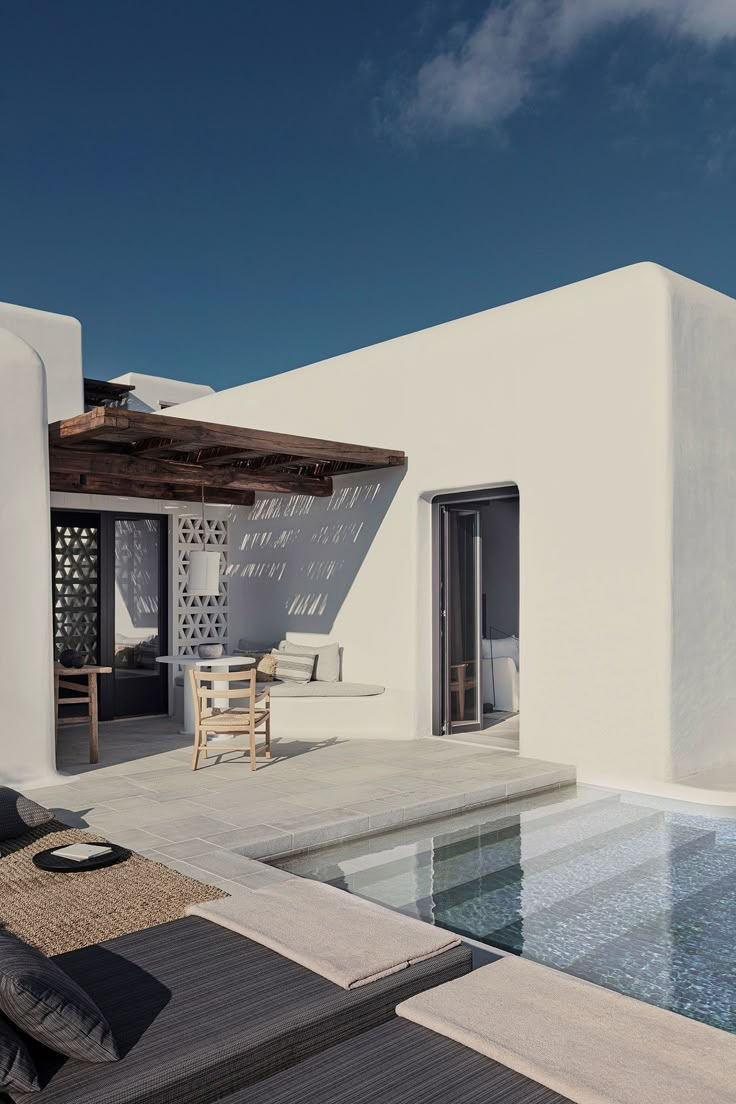 a white house with a pool and patio furniture