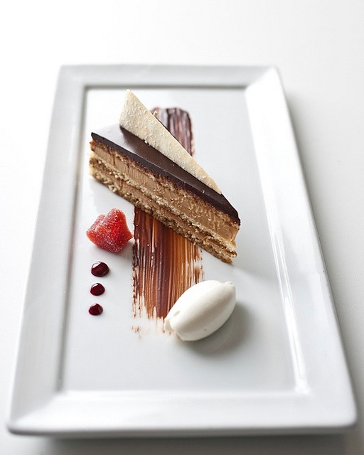 a piece of cake on a white plate with chocolate and strawberries next to it