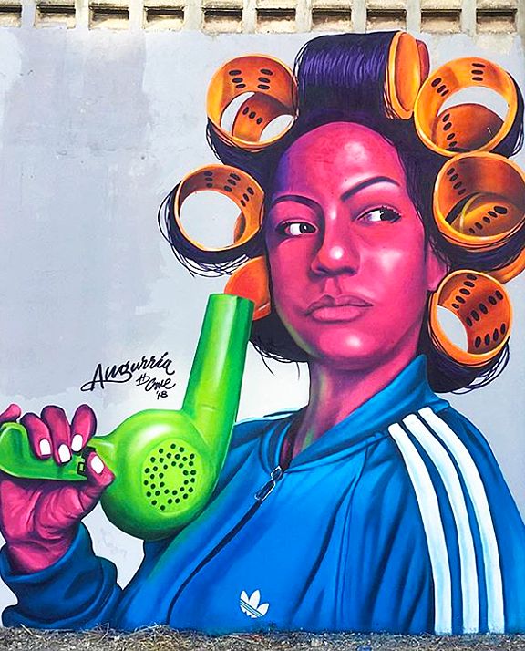 a woman holding a green phone in front of a wall painted with hairdryers