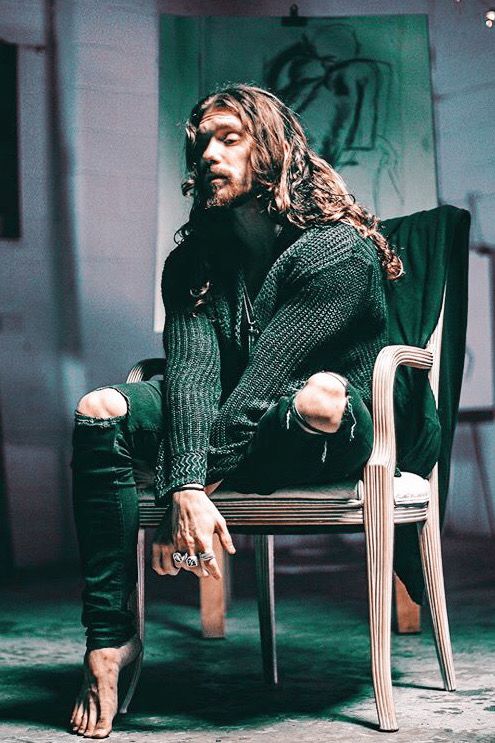 a man with long hair sitting in a chair