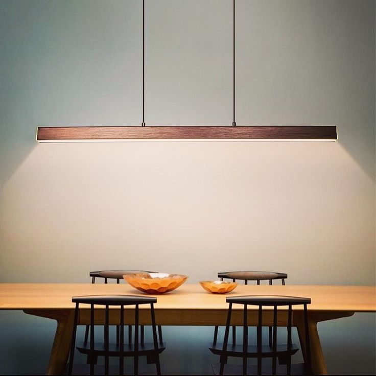 two bowls sit on top of a wooden table with four chairs around it in front of a white wall