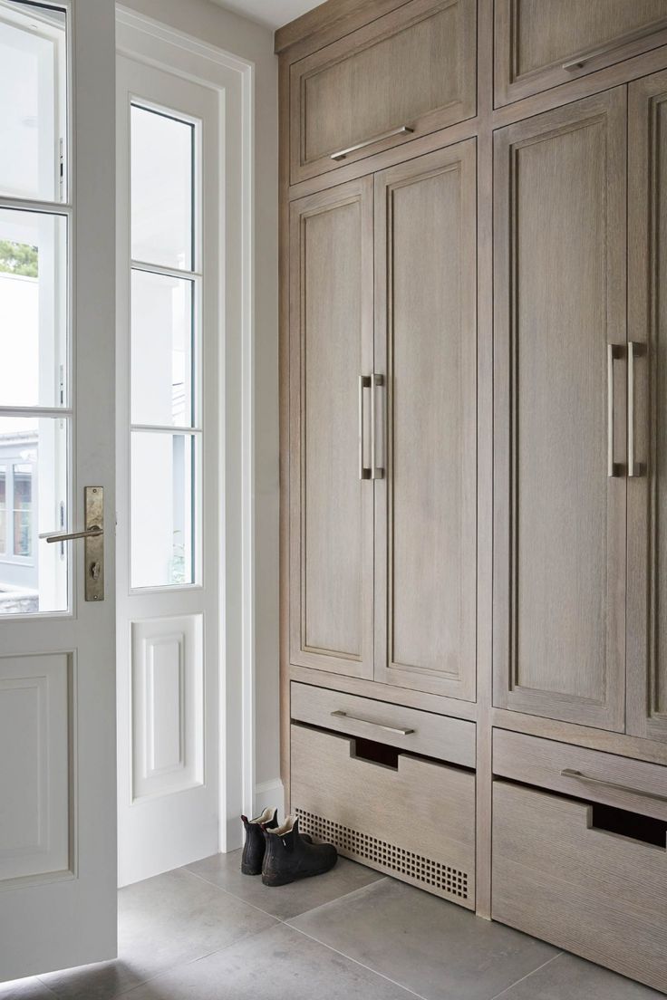 an empty room with large wooden cabinets and doors on either side of the door is a pair of black shoes