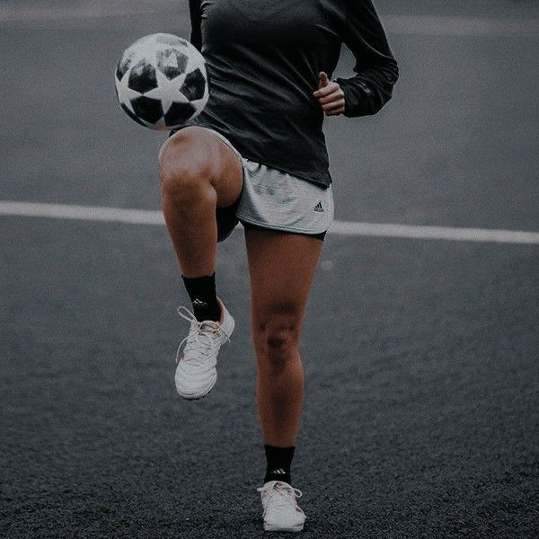 a woman is kicking a soccer ball on the street with her leg in the air