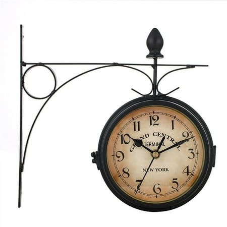 a clock hanging from the side of a metal pole with an iron frame on it