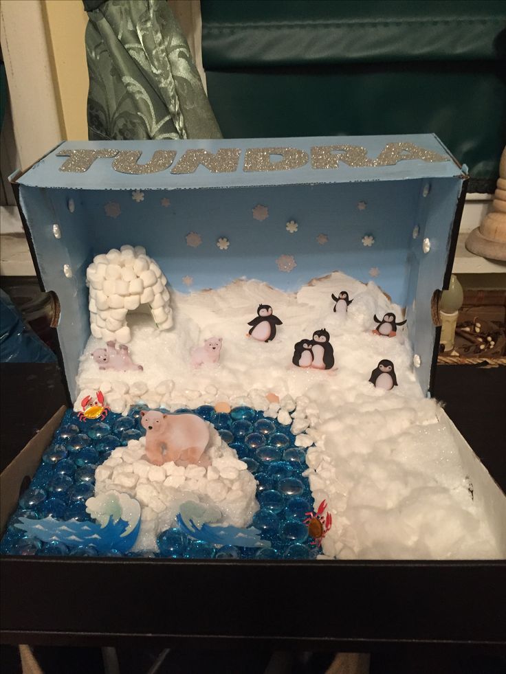 a cake in the shape of a box with penguins and snow around it on a table