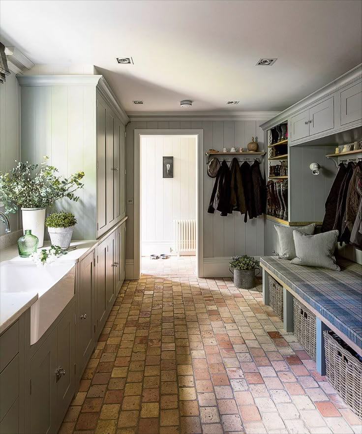 a bathroom with tiled flooring and white cupboards next to a bathtub filled with clothes