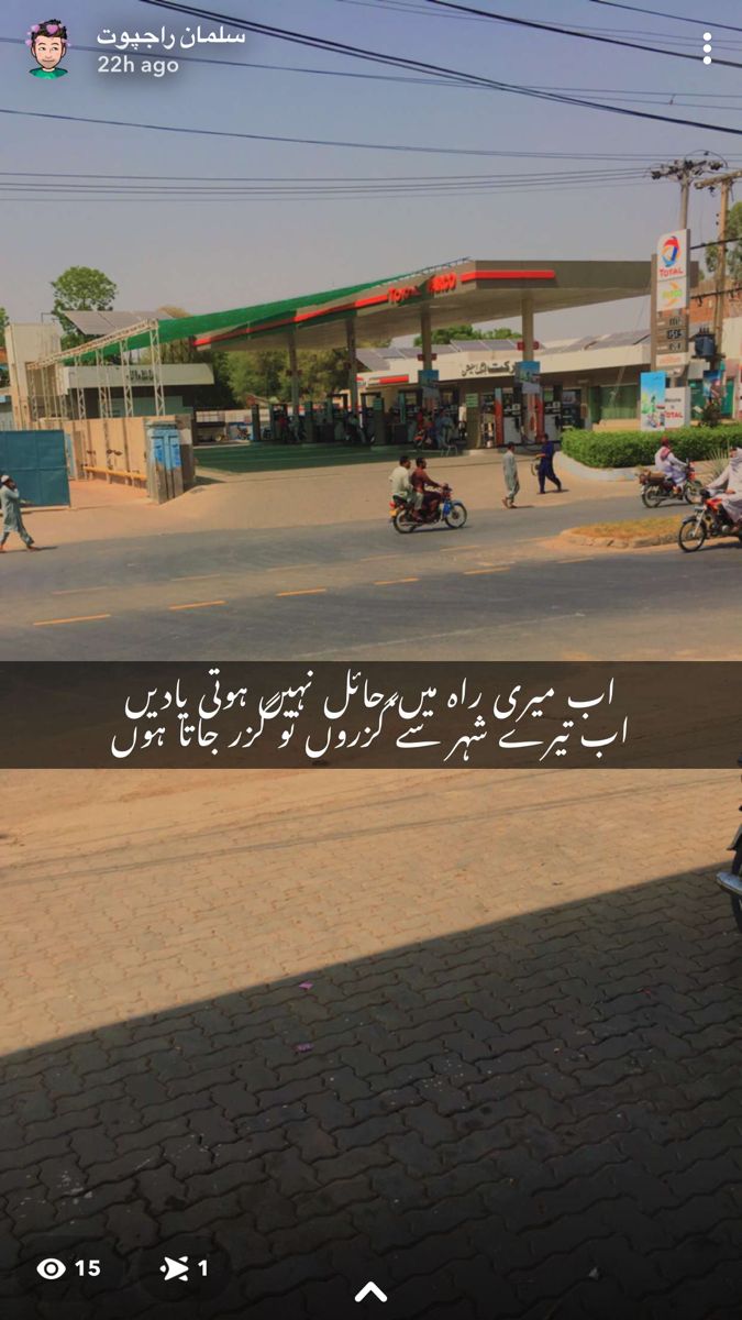 a man riding a motorcycle down a street next to a gas station