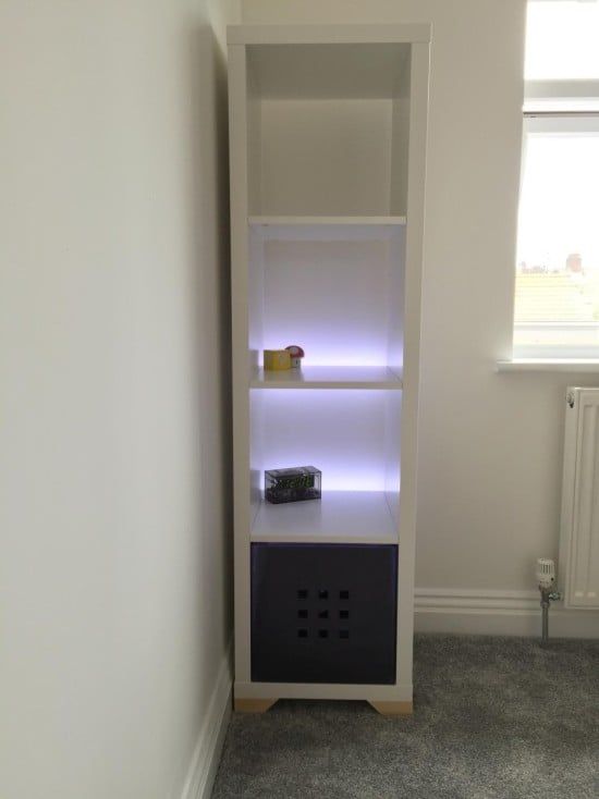 a white shelf with some lights on it next to a radiator in a room