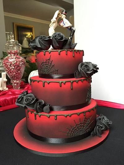 a three tiered cake decorated with red and black icing, on a table