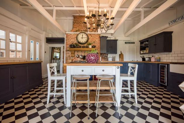 a kitchen with black and white checkered flooring, two stools at the island