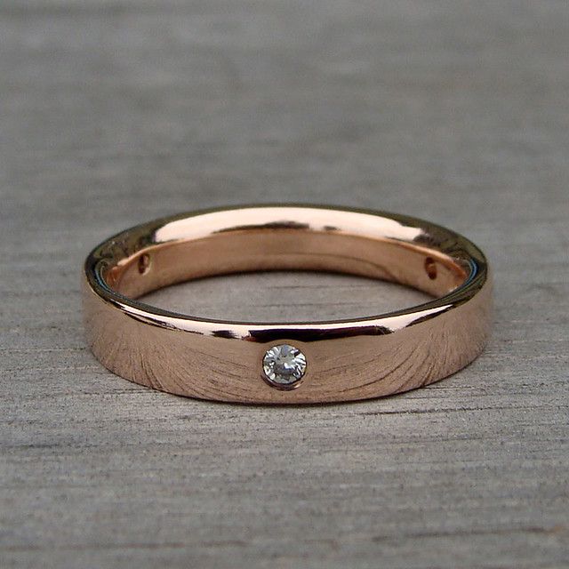 a gold wedding band with a diamond in the center