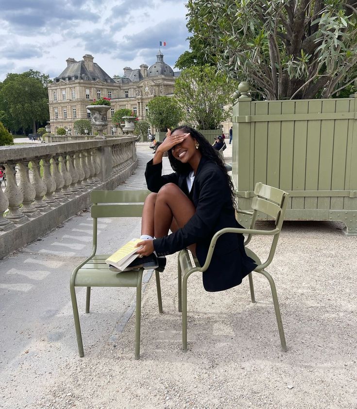 a woman sitting on top of a green chair next to a table with a book