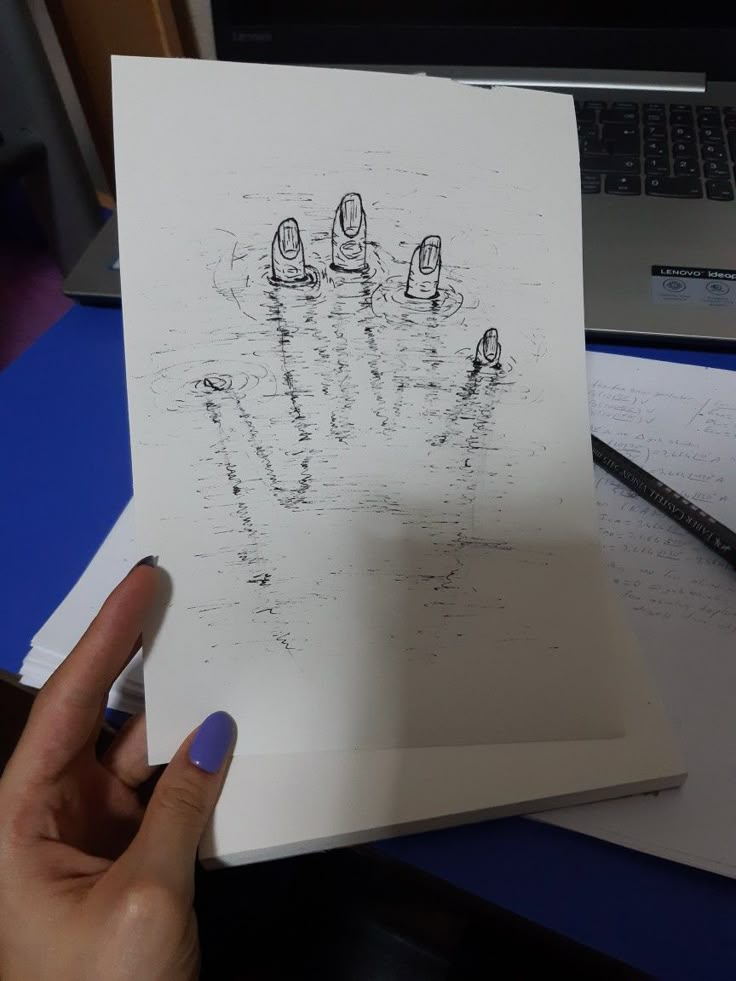 a person holding up a piece of paper with drawings on it