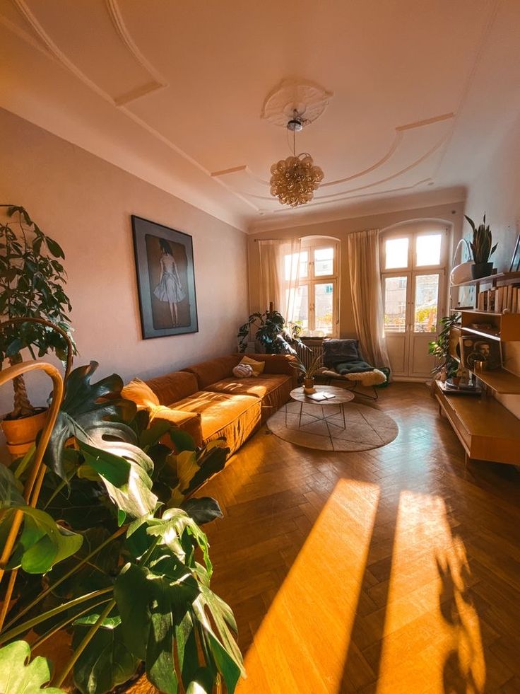 a living room filled with furniture and lots of plants on top of hard wood flooring