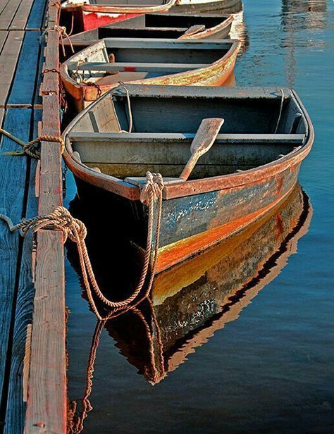 several row boats tied to a dock in the water