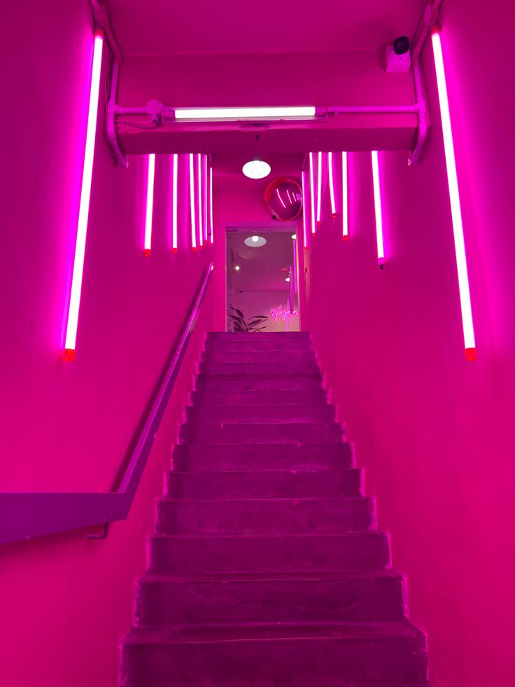 the stairs are lit up with pink lights and purple carpeted steps leading to an exitway