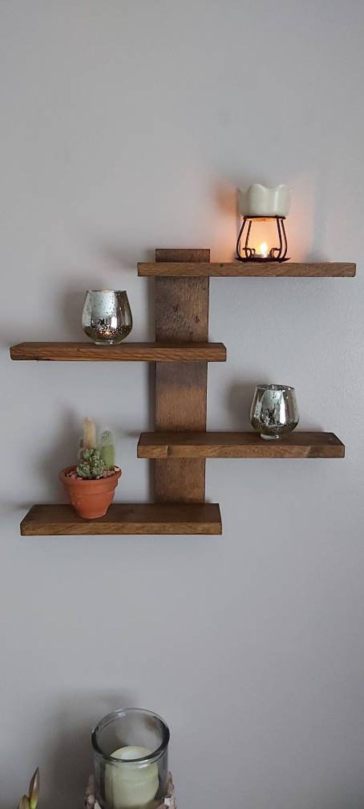 three wooden shelves with candles on them in the corner and one shelf holding two small vases