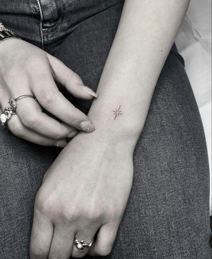 a woman's arm with a small star tattoo on it