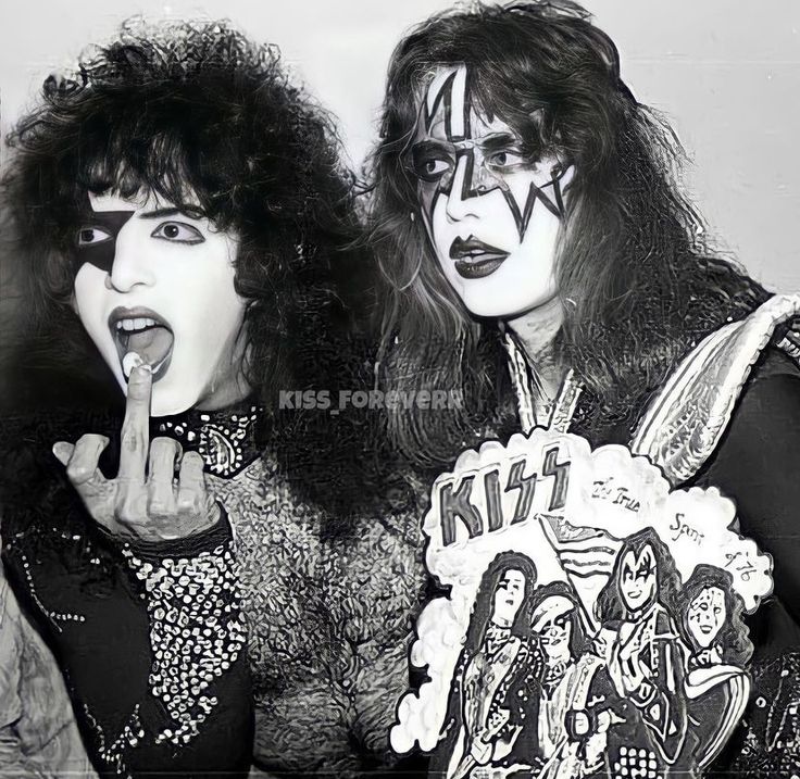 two women dressed as kiss band members posing for the camera with their fingers in their mouths