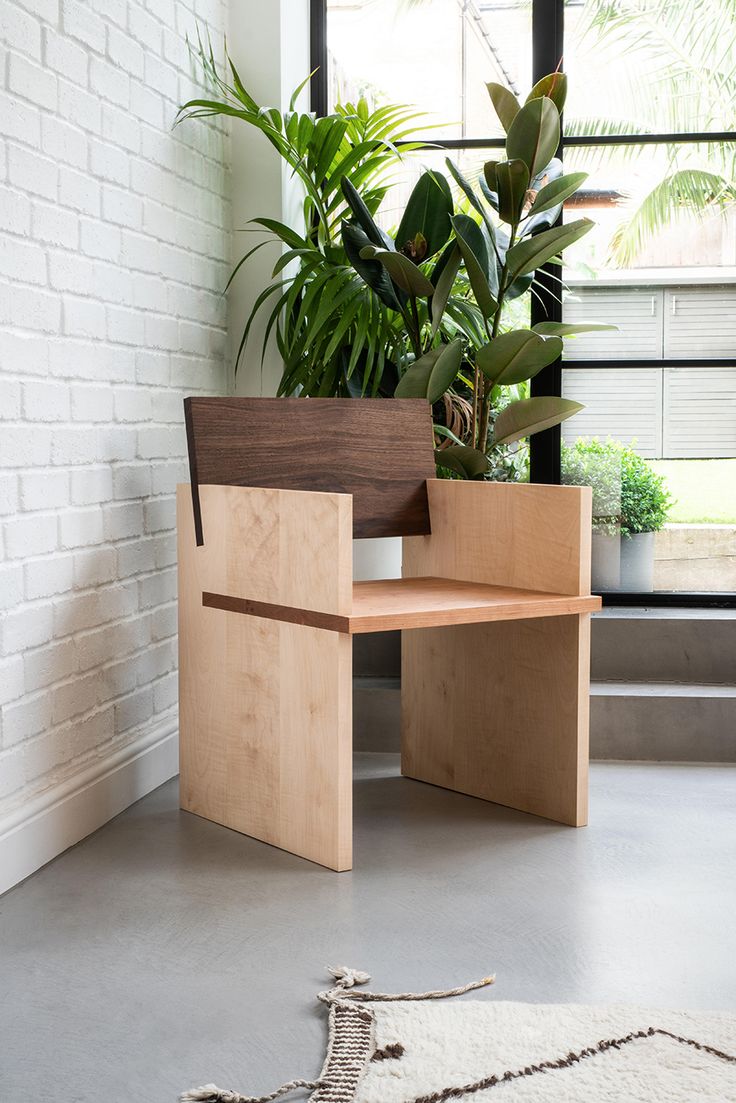 a wooden chair sitting next to a window in front of a potted plant on top of a hard wood floor