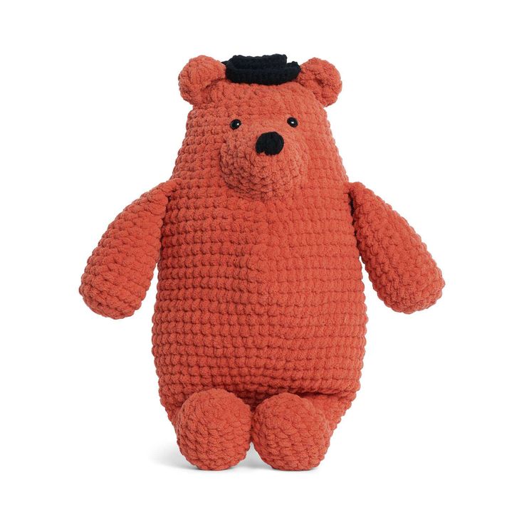 an orange crocheted teddy bear with a black hat