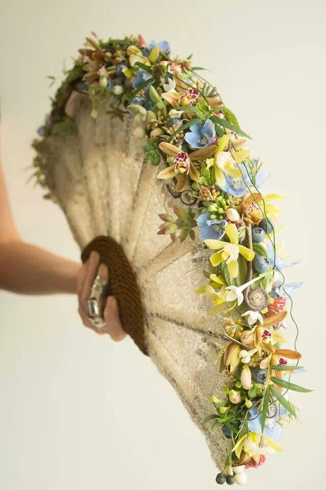 a person holding an old fan with flowers on it