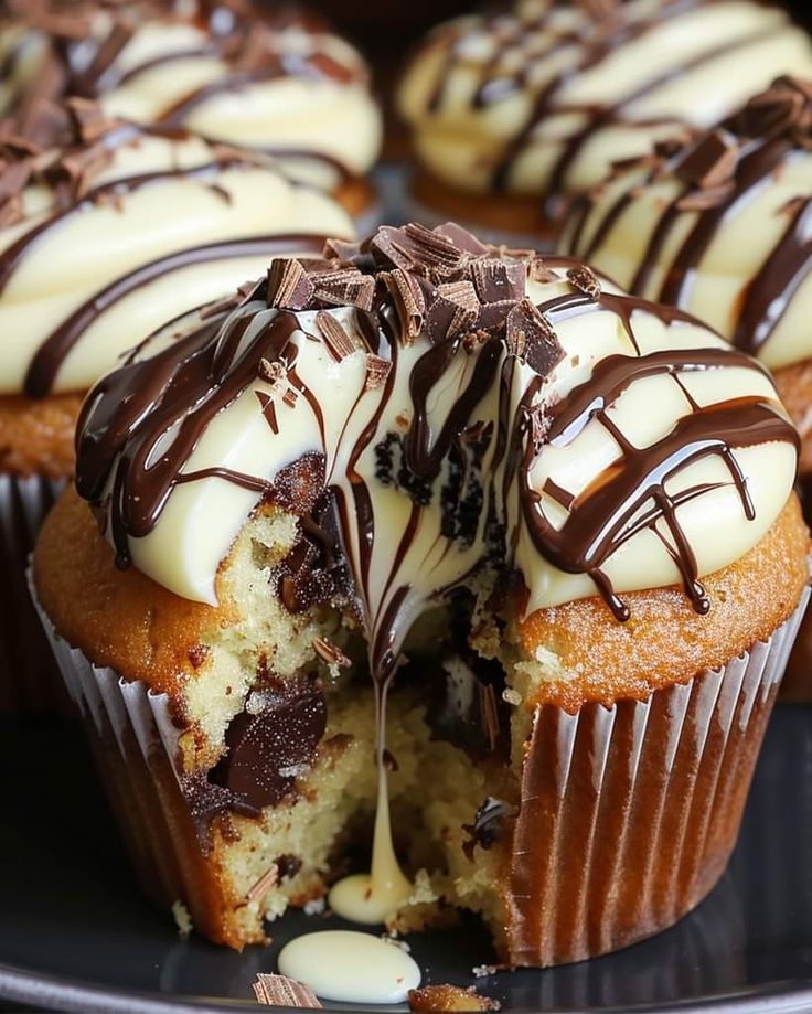 a chocolate cupcake with white frosting and drizzled chocolate on top