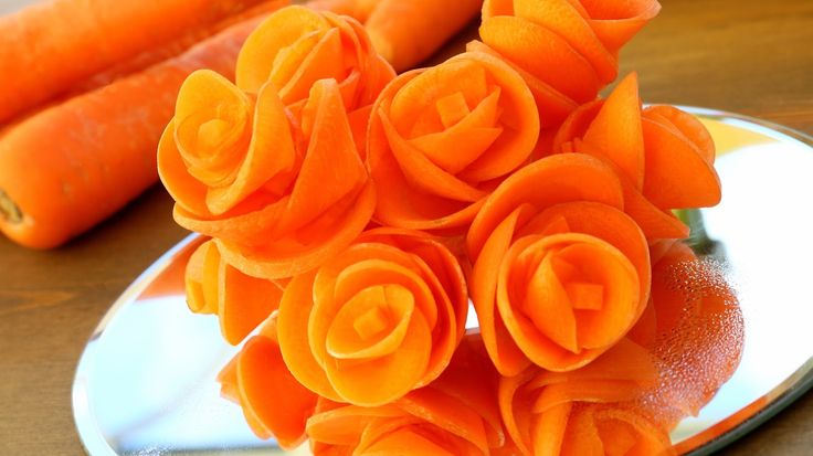 some carrots are sitting on a plate with flowers in the middle and one is orange