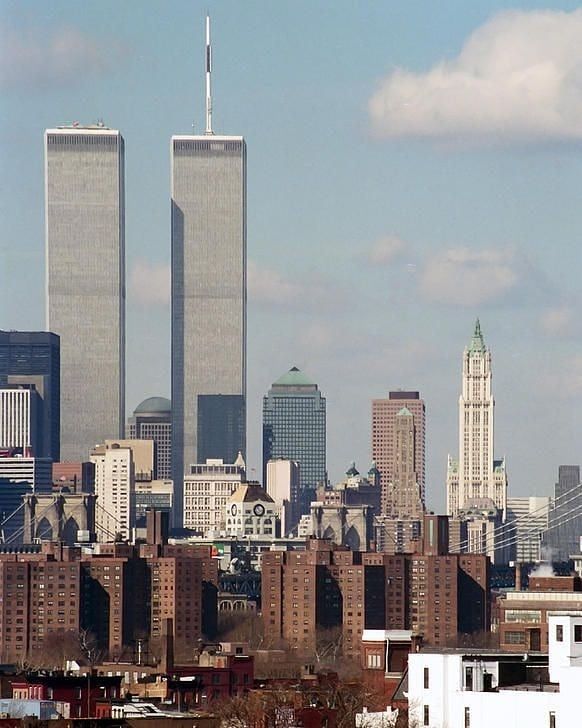 two tall buildings towering over a city with skyscrapers in the backgrounnd