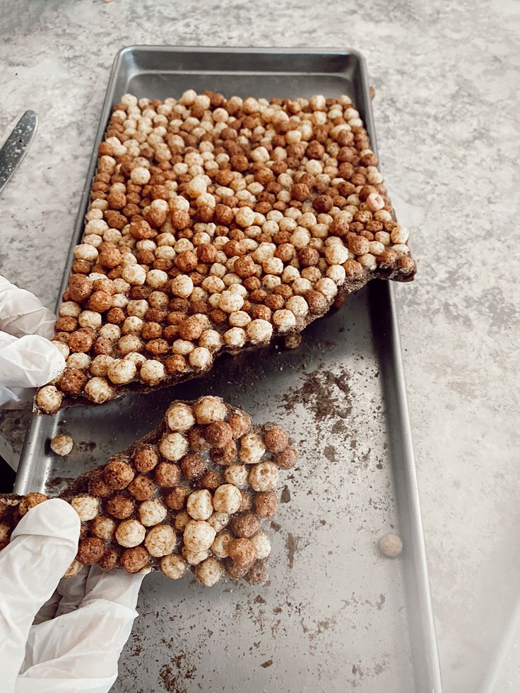 a person in white gloves holding a pan filled with food